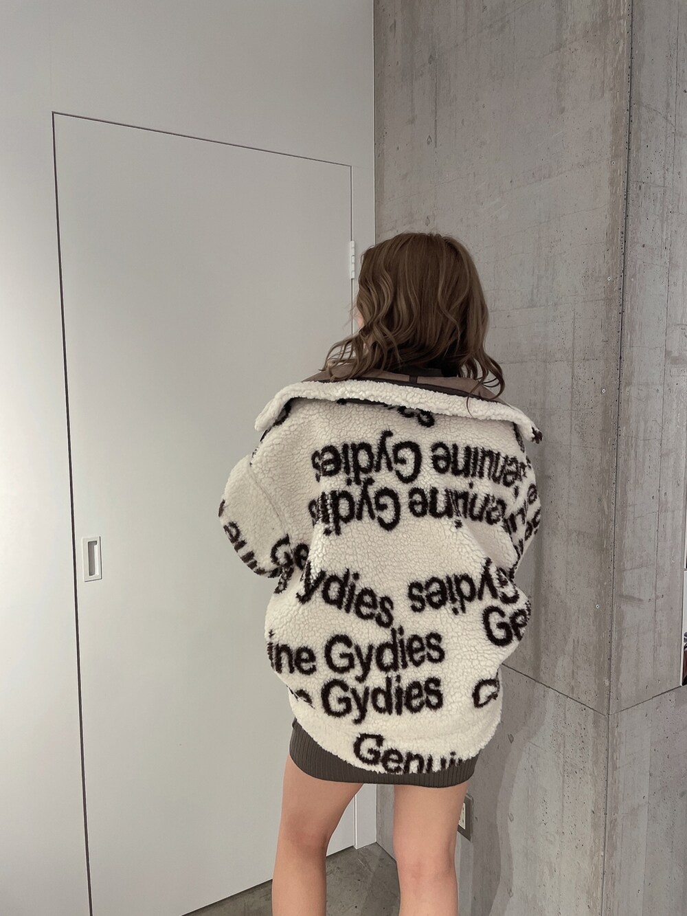 ホワイト系のブルゾン、グリーン系のワンピース、ブラック系のブーツを着用したレディースの冬コーディネートの6枚目の写真