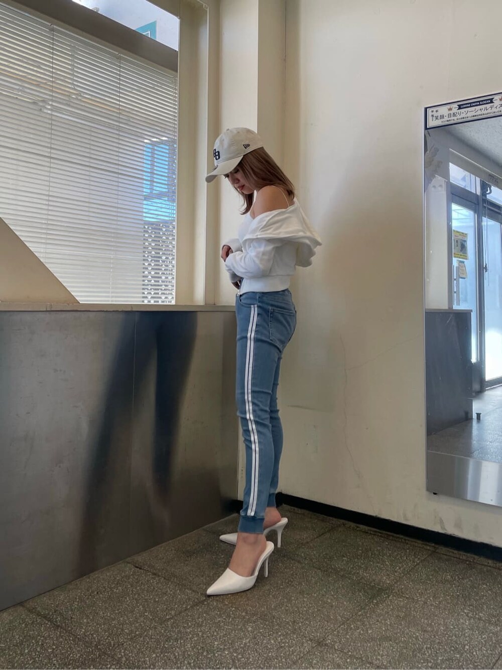 ホワイト系のパーカー、ホワイト系のパンプス、ブルー系のデニムパンツを着用したレディースの冬コーディネートの3枚目の写真