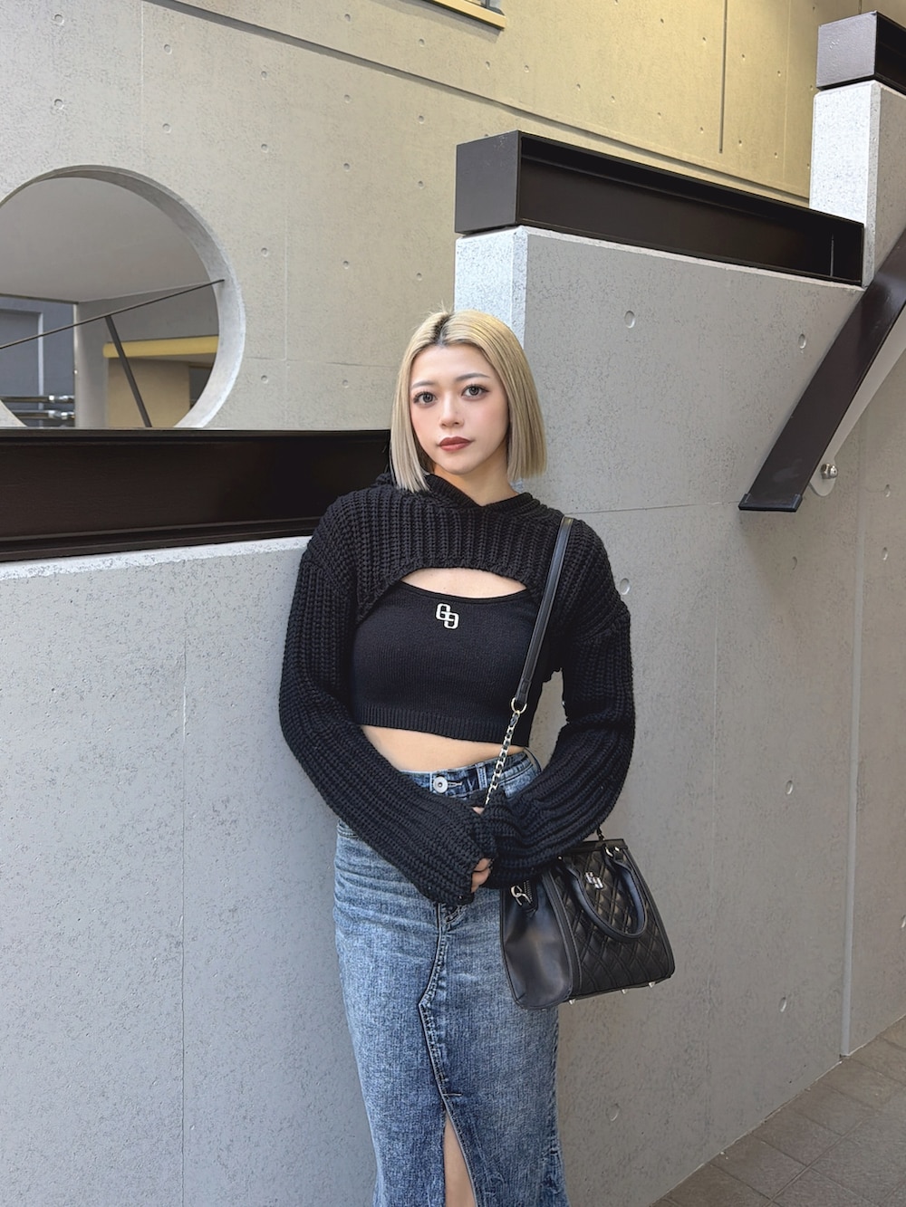 ブラック系のニット/セーター、ブルー系のデニムスカート、ブラック系のブーツを着用したレディースの冬コーディネートの3枚目の写真