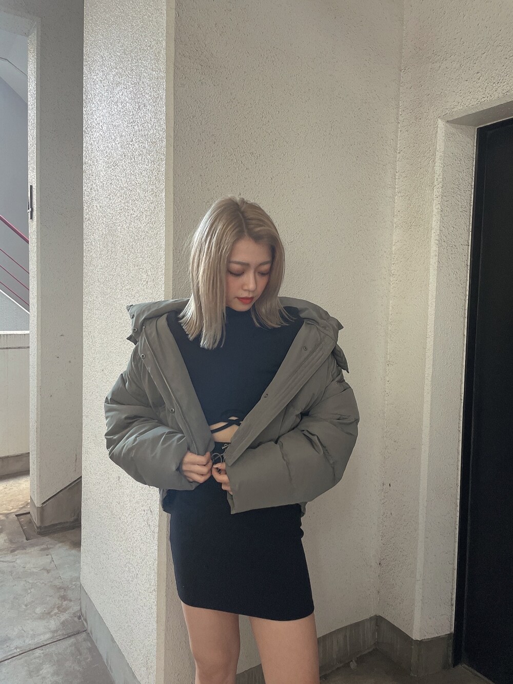 グリーン系のダウンジャケット/コート、ブラック系のワンピース、ブラック系のブーツを着用したレディースの秋コーディネートの5枚目の写真