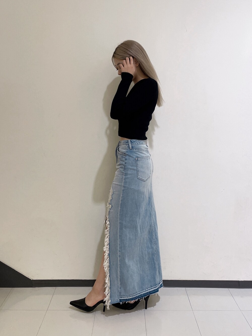 ブラック系のニット/セーター、ブルー系のデニムスカート、ブラック系のパンプスを着用したレディースの秋コーディネートの4枚目の写真