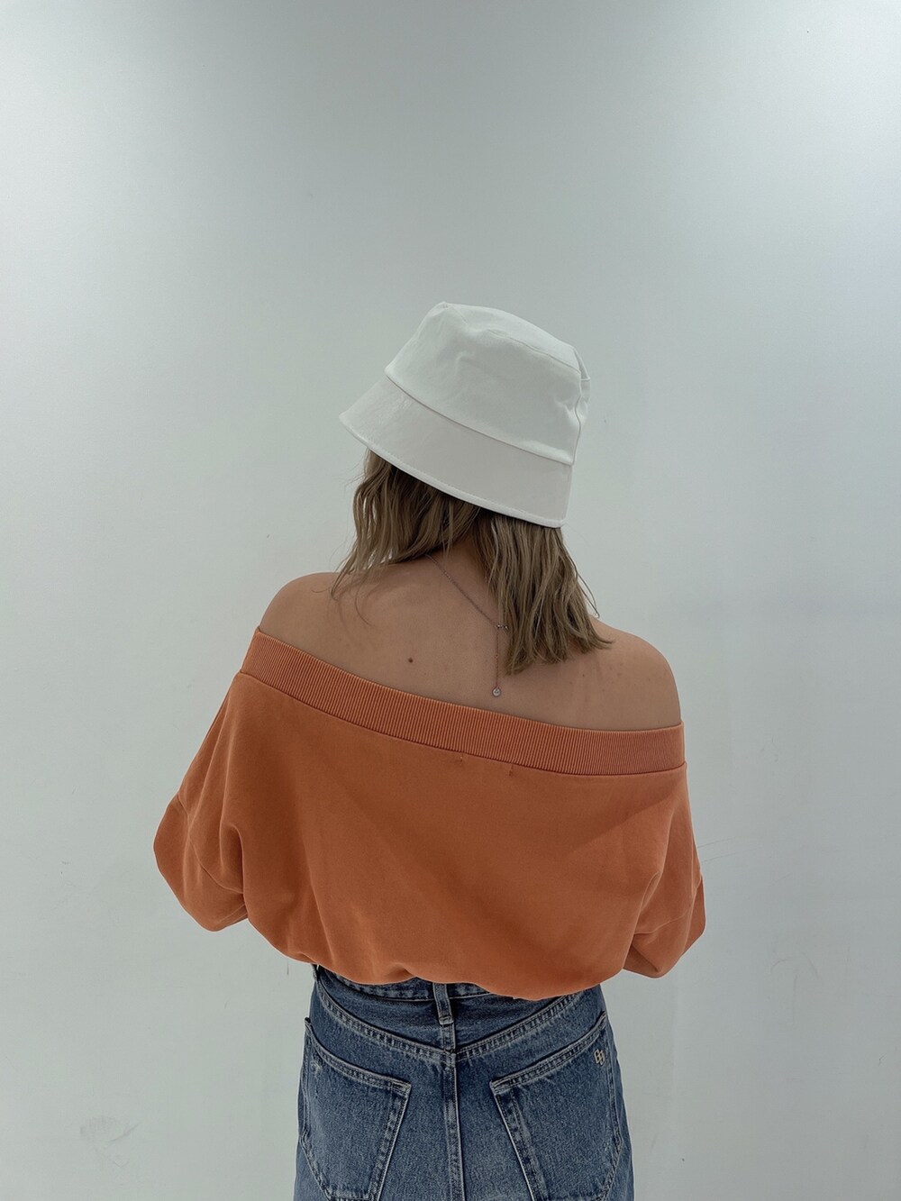 オレンジ系のTシャツ/カットソー、ブルー系のデニムパンツ、ホワイト系のパンプスを着用したレディースの冬コーディネートの5枚目の写真