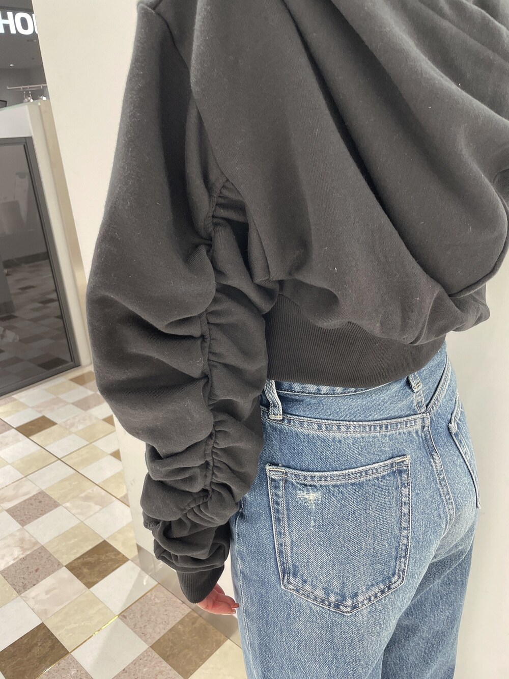 ブラック系のパーカー、ブルー系のデニムパンツ、ブラック系のパンプスを着用したレディースの冬コーディネートの5枚目の写真