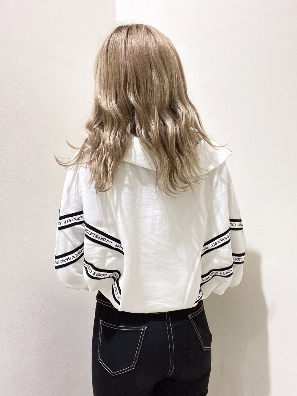 ホワイト系のスウェット、ブラック系のデニムパンツ、ブラック系のブーツを着用したレディースの秋コーディネートの4枚目の写真