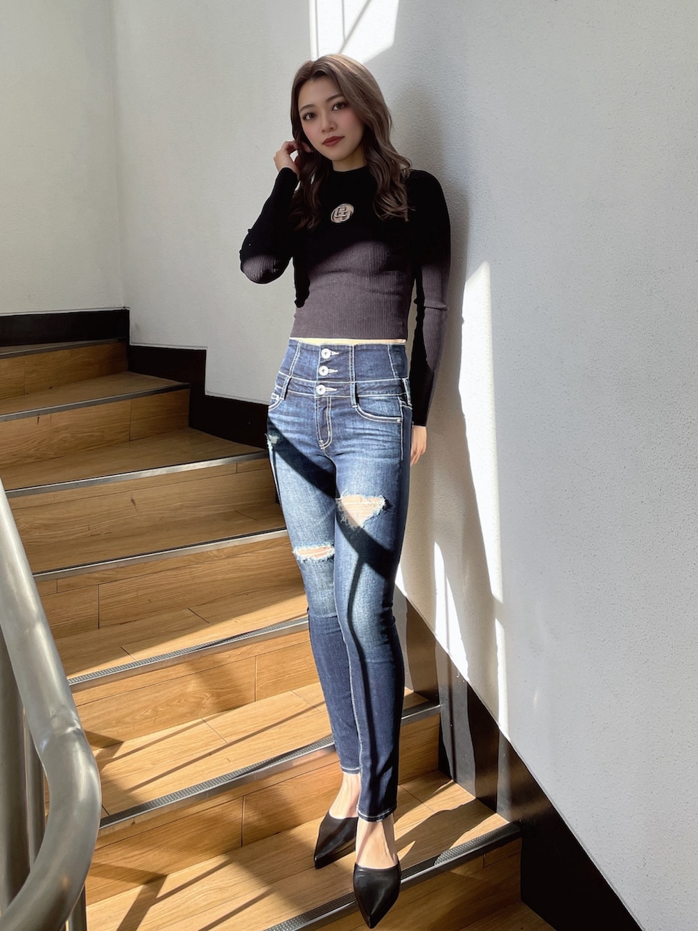 ブラック系のニット/セーター、ブラック系のパンプス、ブルー系のデニムパンツを着用したレディースの冬コーディネートの2枚目の写真