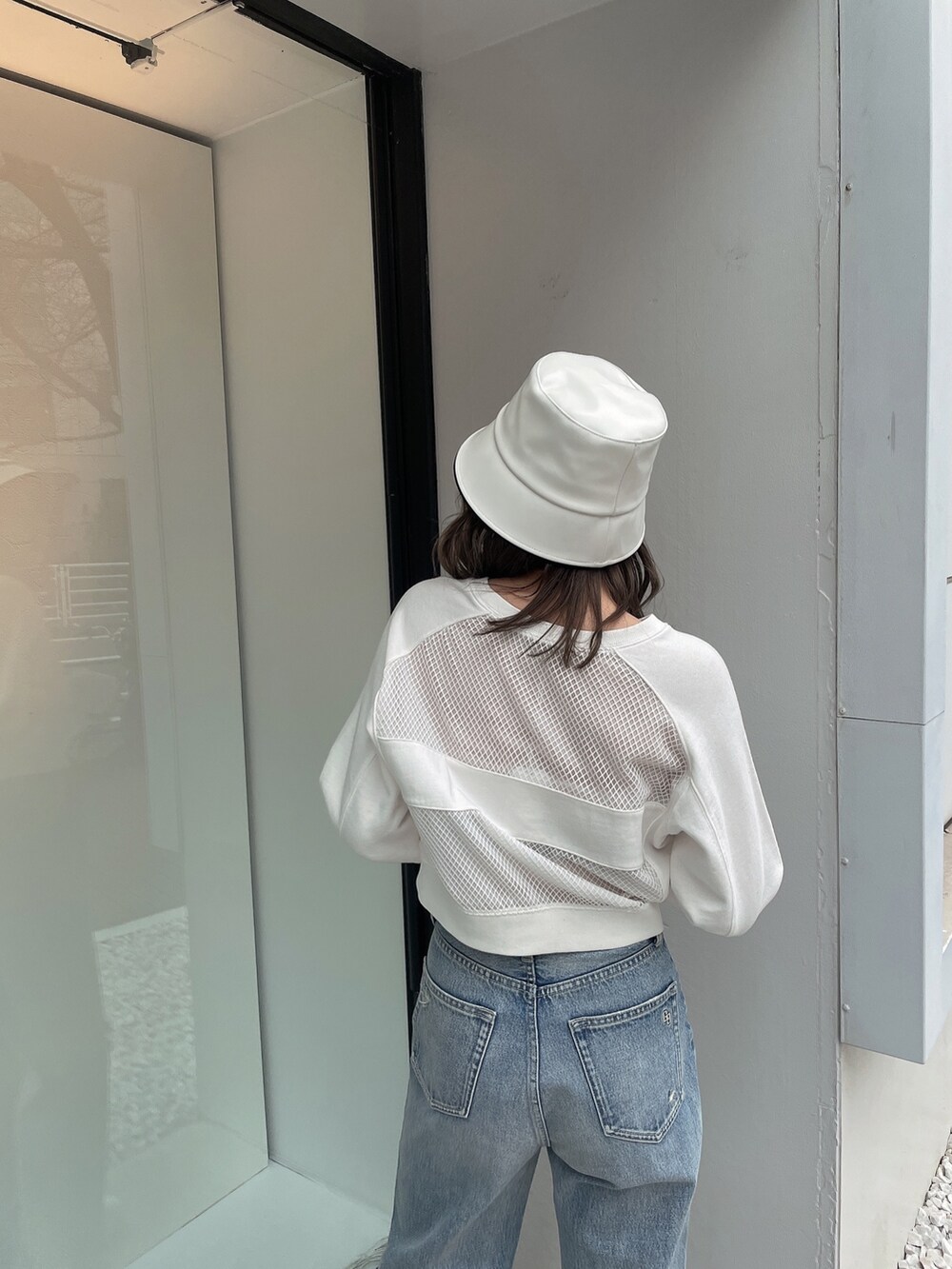 ホワイト系のスウェット、ブルー系のデニムパンツ、ホワイト系のスニーカーを着用したレディースの冬コーディネートの5枚目の写真