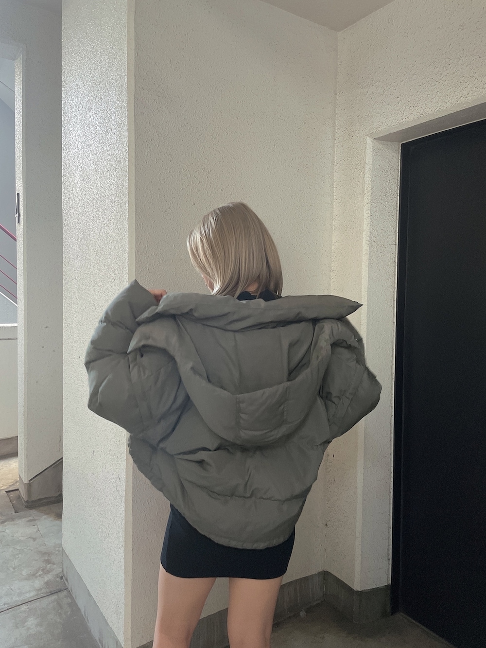 グリーン系のダウンジャケット/コート、ブラック系のワンピース、ブラック系のブーツを着用したレディースの秋コーディネートの6枚目の写真