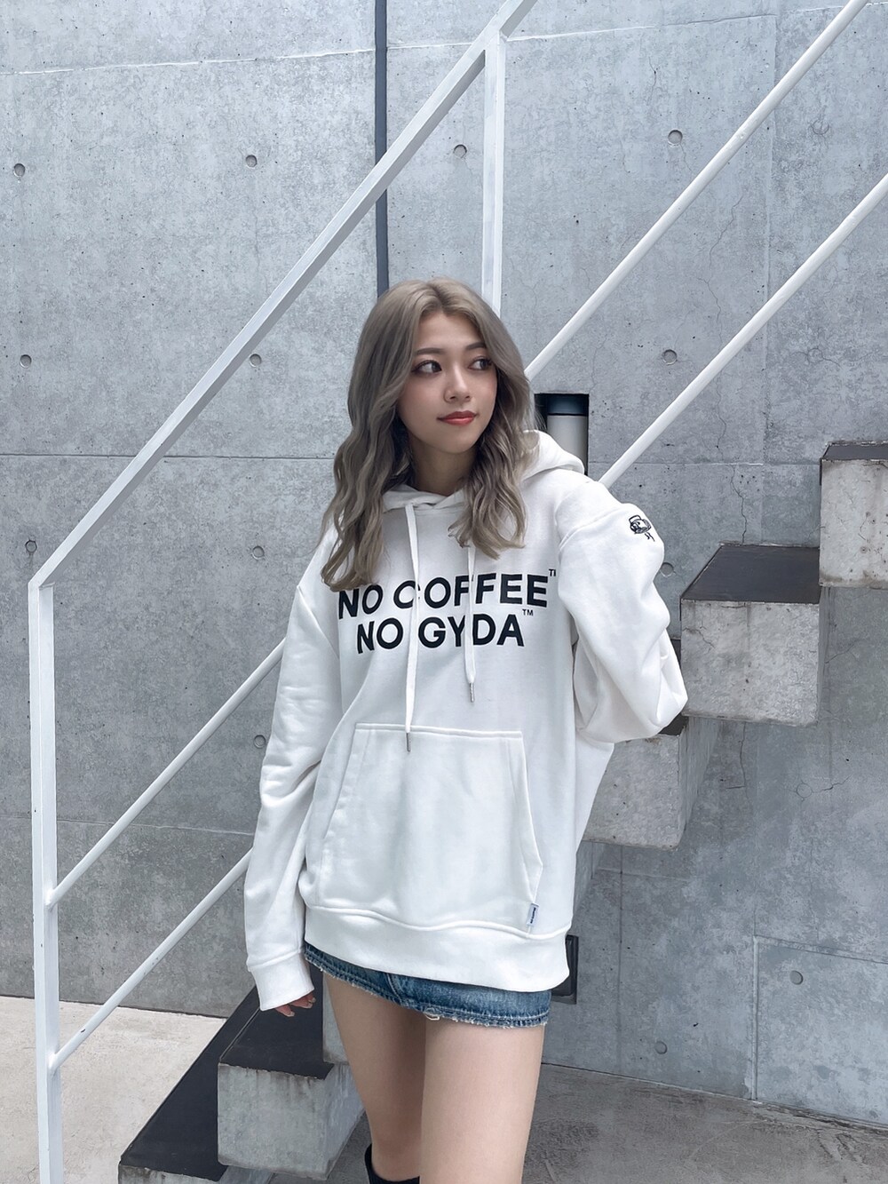 ホワイト系のパーカー、ブルー系のデニムスカート、ブラック系のブーツを着用したレディースの秋コーディネートの5枚目の写真