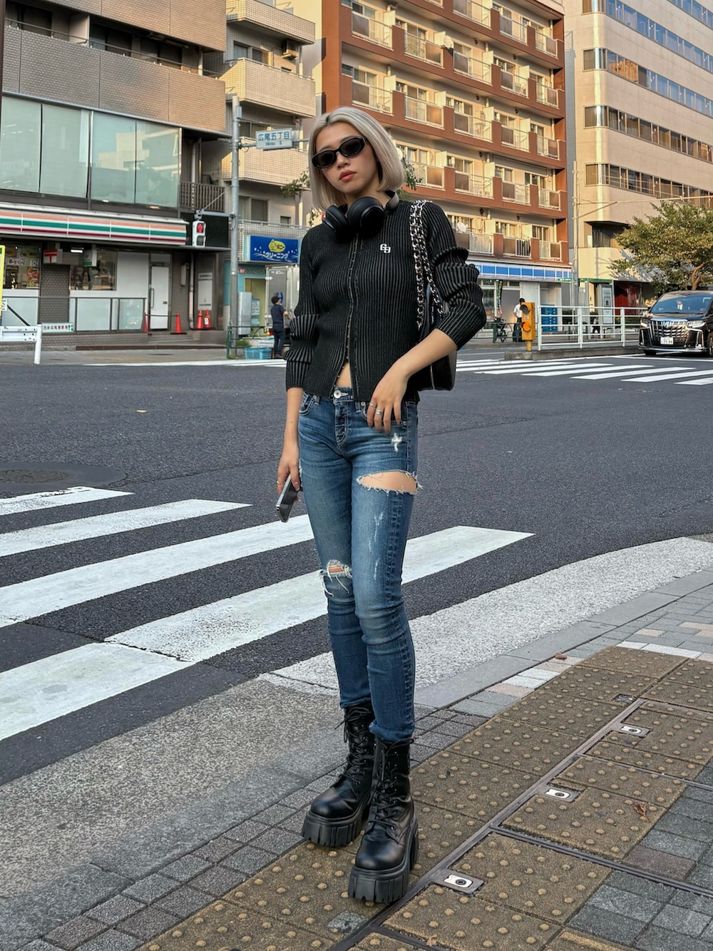 ブラック系のニット/セーター、ブルー系のデニムパンツ、ブラック系のブーツを着用したレディースの秋コーディネートの2枚目の写真