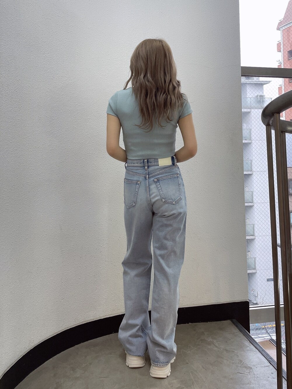 グリーン系のTシャツ/カットソー、ブルー系のデニムパンツ、ホワイト系のスニーカーを着用したレディースの春コーディネートの3枚目の写真