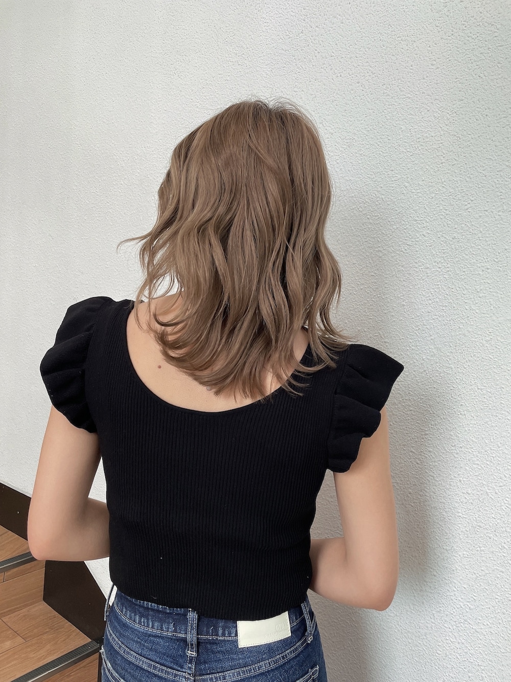 ブラック系のニット/セーター、ホワイト系のハンドバッグ、ブルー系のデニムパンツを着用したレディースの春コーディネートの5枚目の写真