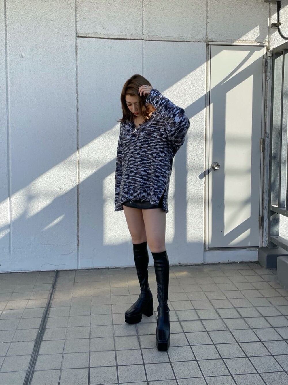 グレー系のニット/セーター、ブラック系のスカート、ブラック系のブーツを着用したレディースの秋コーディネートの3枚目の写真