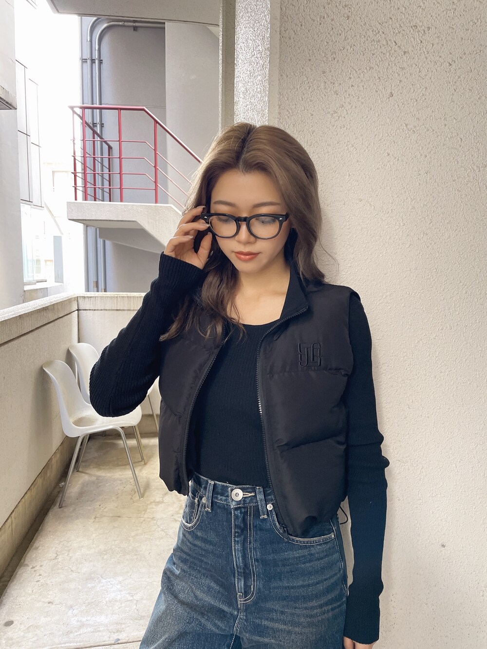 ブラック系のベスト、ブルー系のデニムパンツ、ブラック系のパンプスを着用したレディースの秋コーディネートの3枚目の写真