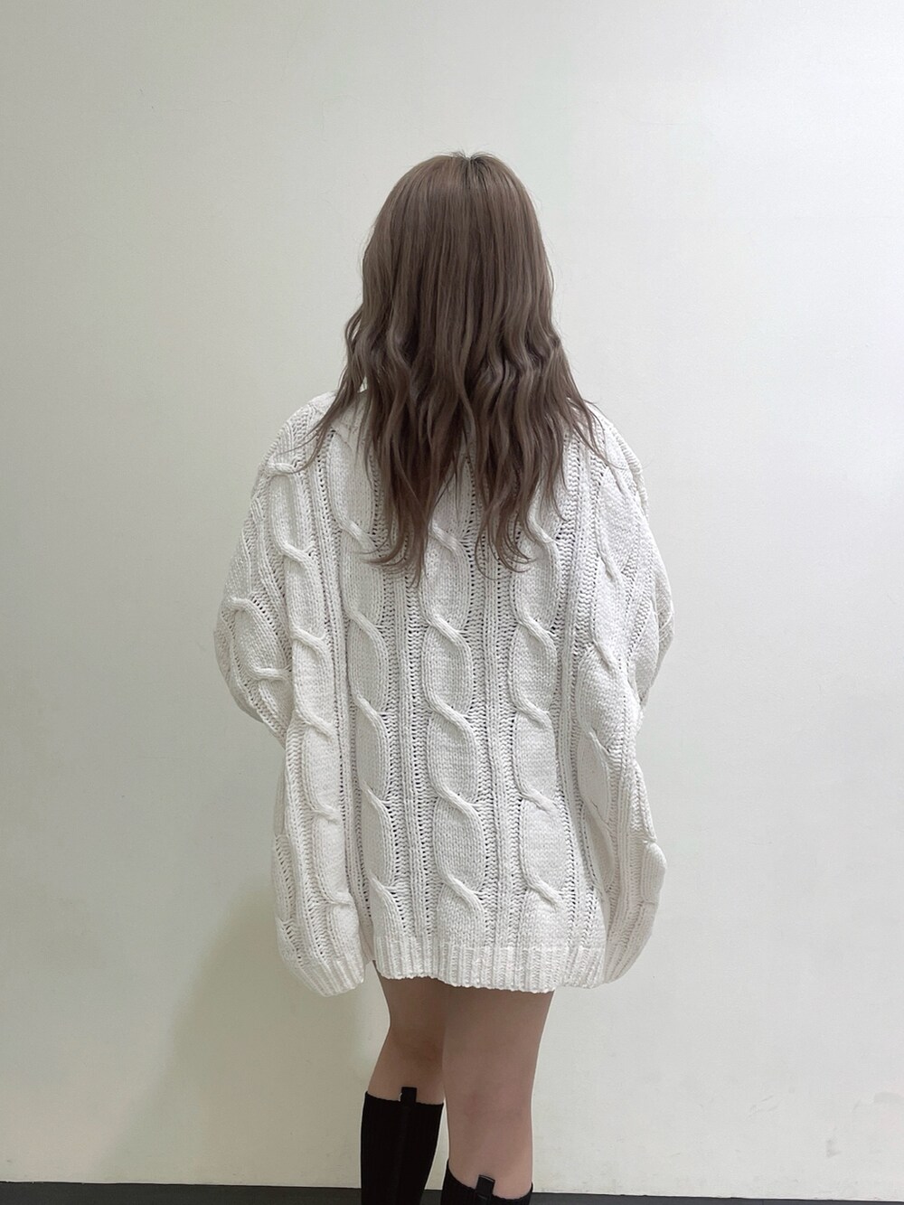 ホワイト系のカーディガン/ボレロ、ブラック系のデニムスカート、ブラック系のブーツを着用したレディースの冬コーディネートの5枚目の写真