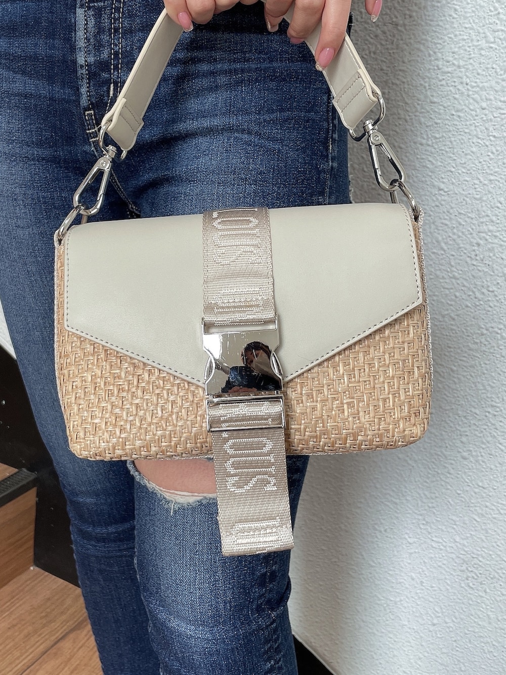 ブラック系のニット/セーター、ホワイト系のハンドバッグ、ブルー系のデニムパンツを着用したレディースの春コーディネートの8枚目の写真