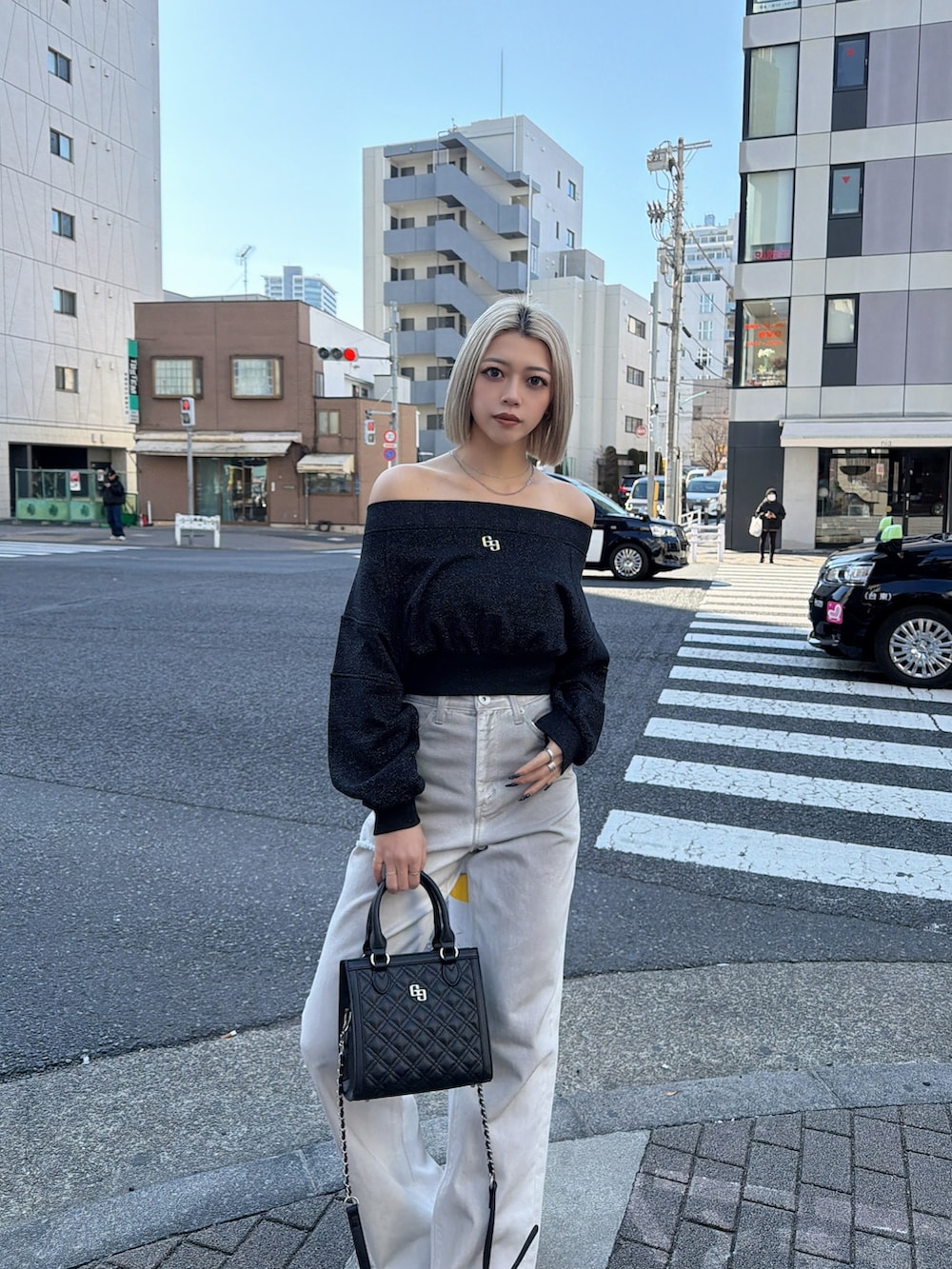 ブラック系のTシャツ/カットソー、ホワイト系のデニムパンツ、ブラック系のショルダーバッグを着用したレディースの冬コーディネートの3枚目の写真