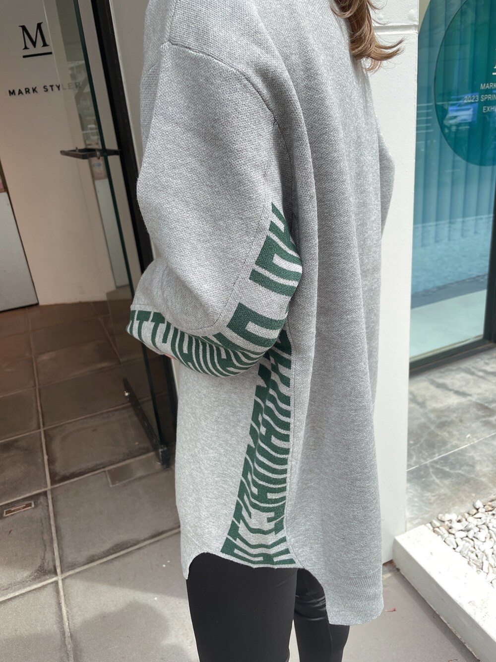 グレー系のニット/セーター、ブラック系のその他パンツ、ブラック系のパンプスを着用したレディースの春コーディネートの6枚目の写真