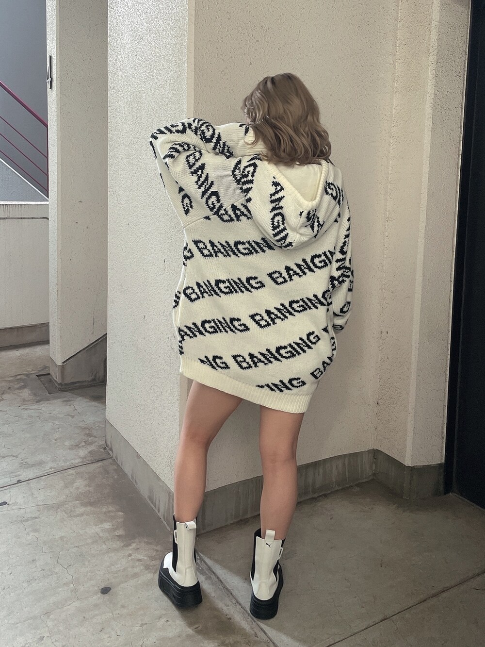 ホワイト系のニット/セーター、ホワイト系のブーツを着用したレディースの冬コーディネートの2枚目の写真