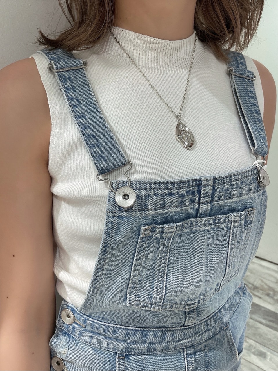 ブルー系のジャンパースカート、ベージュ系のサンダル、ホワイト系のニット/セーターを着用したレディースの春コーディネートの3枚目の写真