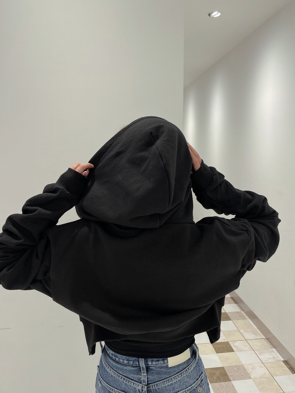 ブラック系のパーカー、ブルー系のデニムパンツ、ブラック系のパンプスを着用したレディースの冬コーディネートの4枚目の写真