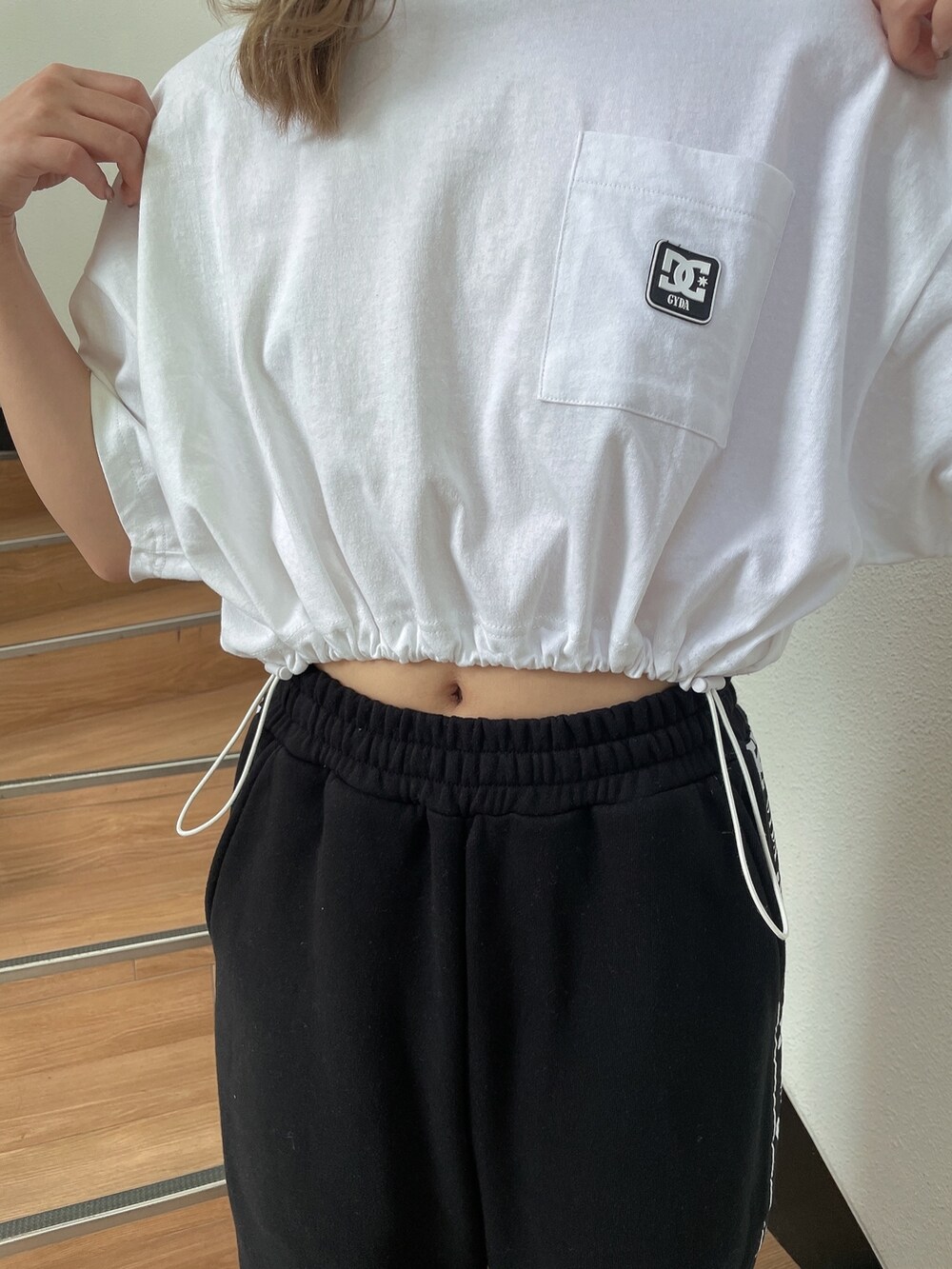 ホワイト系のTシャツ/カットソー、ブラック系のスウェットパンツ、ホワイト系のパンプスを着用したレディースの春コーディネートの6枚目の写真