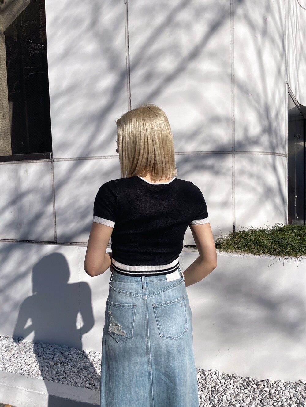 ブラック系のニット/セーター、ブルー系のデニムスカート、ブラック系のパンプスを着用したレディースの春コーディネートの3枚目の写真