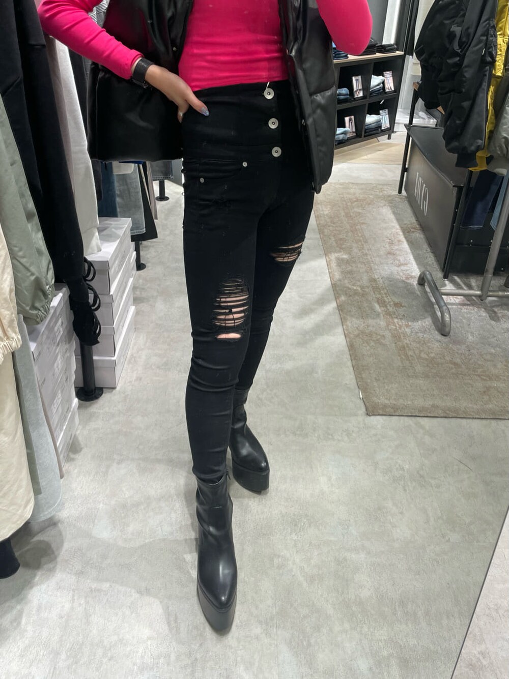 ブラック系のブーツ、ブラック系のデニムパンツ、ブラック系のベストを着用したレディースの秋コーディネートの6枚目の写真