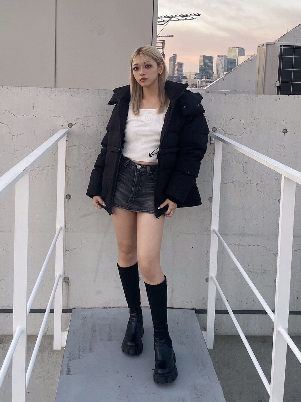 ブラック系のダウンジャケット/コート、ブラック系のデニムスカート、ホワイト系のニット/セーターを着用したレディースの冬コーディネートの2枚目の写真