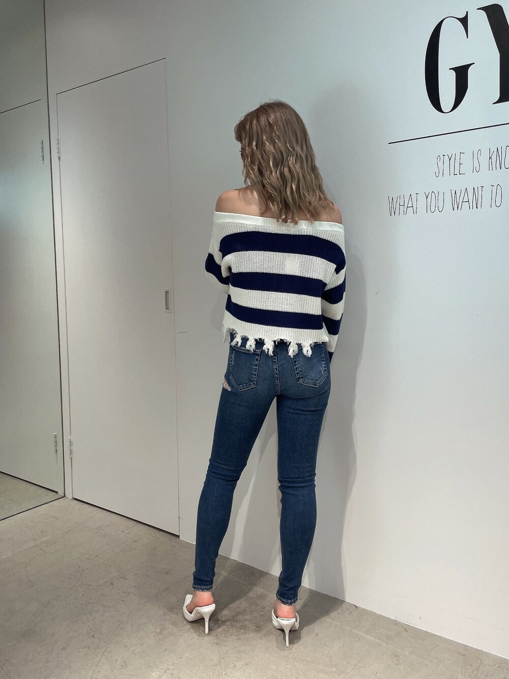ブルー系のニット/セーター、ブルー系のデニムパンツ、ホワイト系のパンプスを着用したレディースの夏コーディネートの3枚目の写真