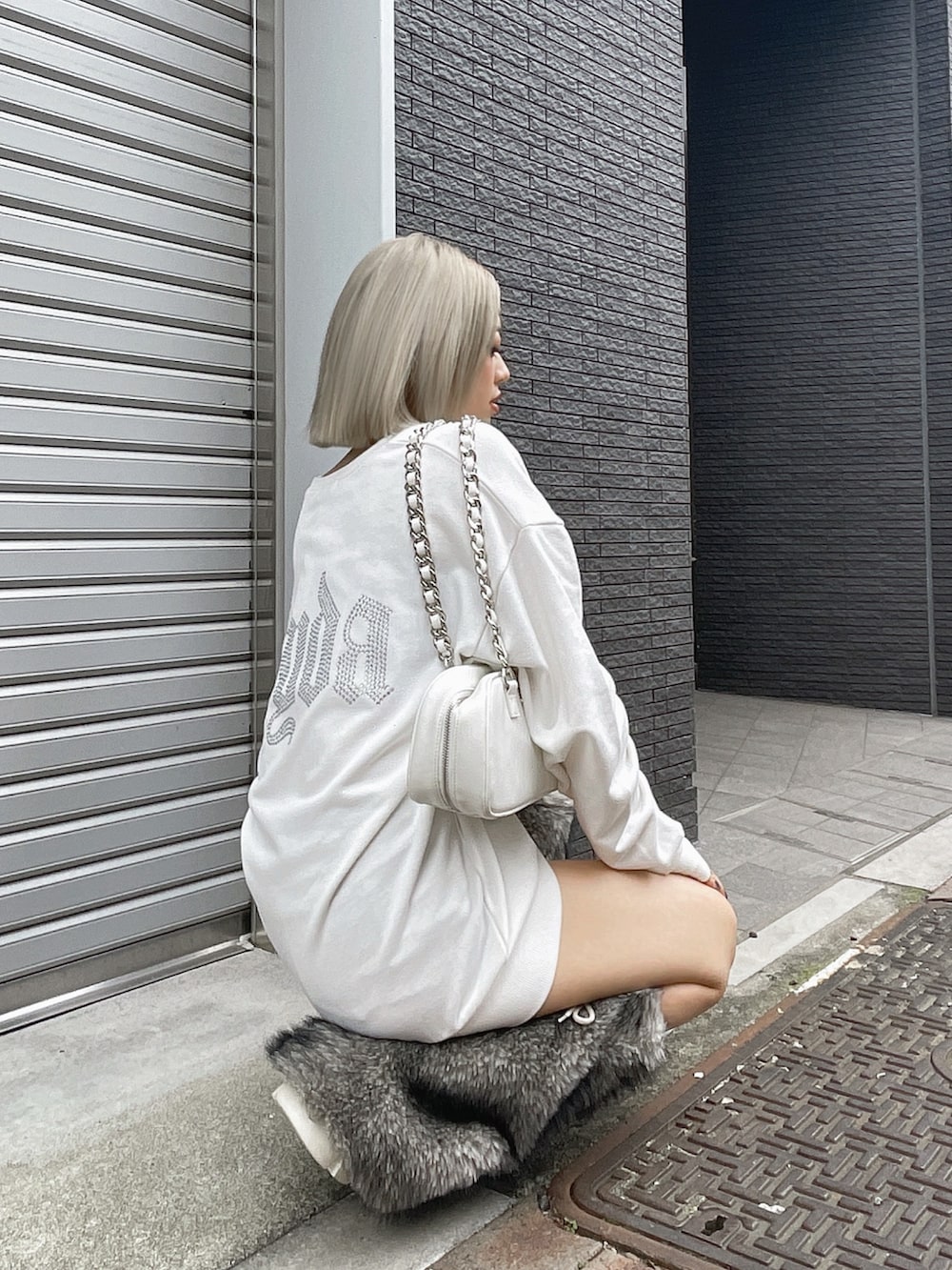 ホワイト系のパーカー、ホワイト系のブーツ、ホワイト系のショルダーバッグを着用したレディースの秋コーディネートの2枚目の写真