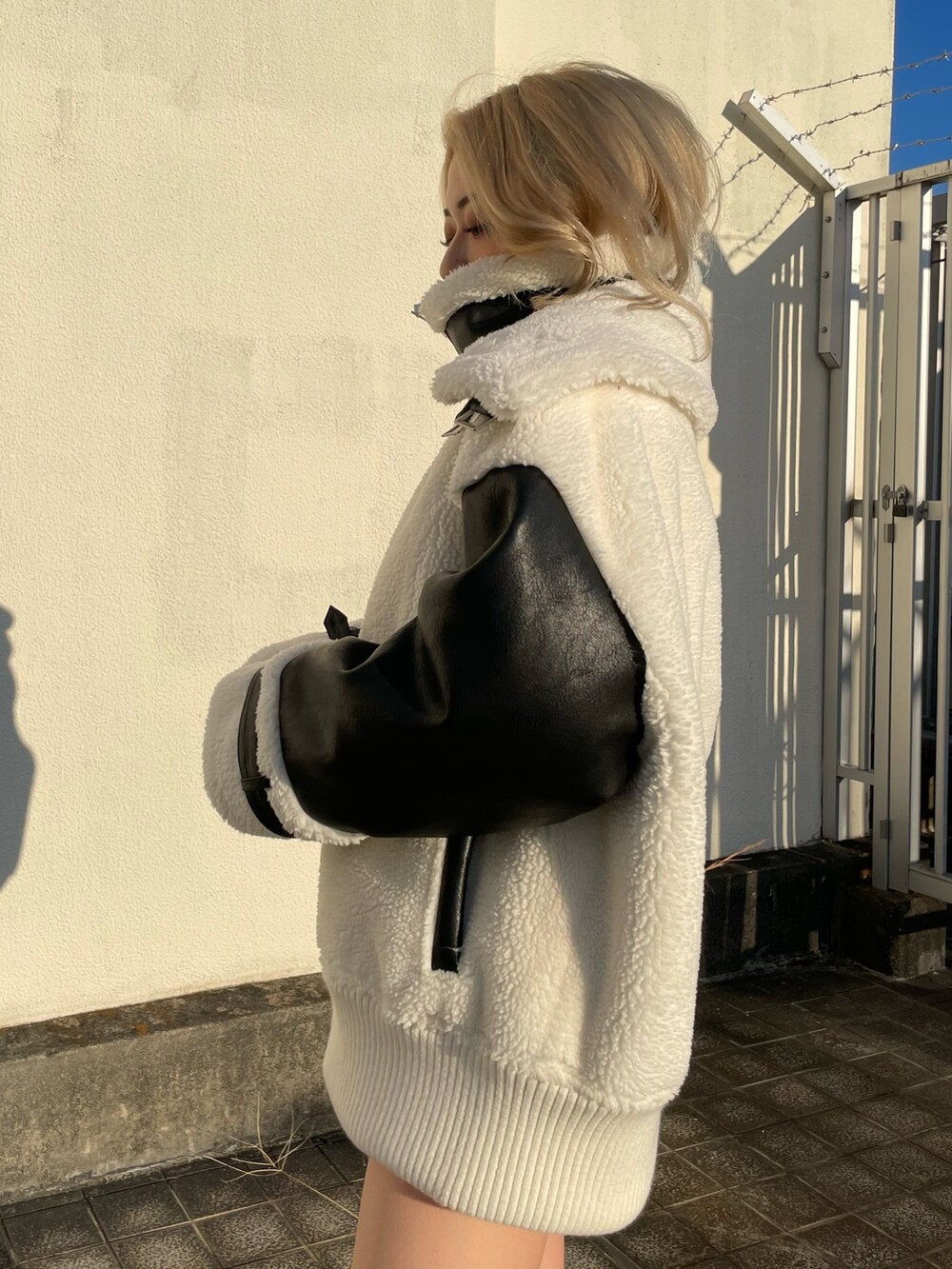 ホワイト系のブルゾン、ブラック系のブーツを着用したレディースの秋コーディネートの4枚目の写真