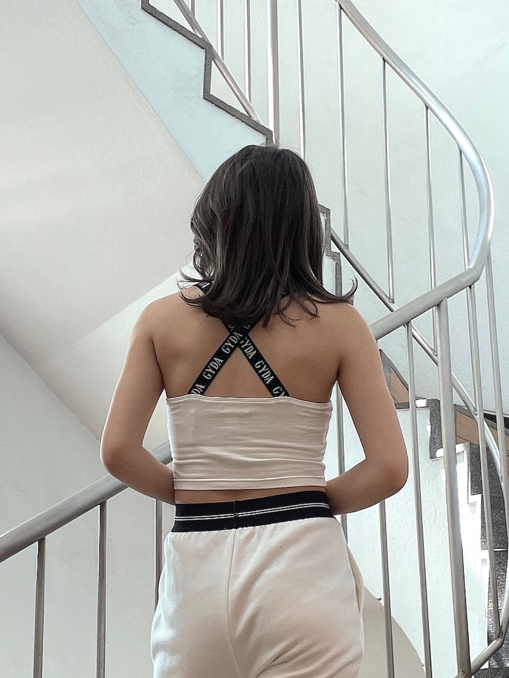 ホワイト系のスウェットパンツ、ホワイト系のタンクトップ、ブラック系のサンダルを着用したレディースの春コーディネートの5枚目の写真