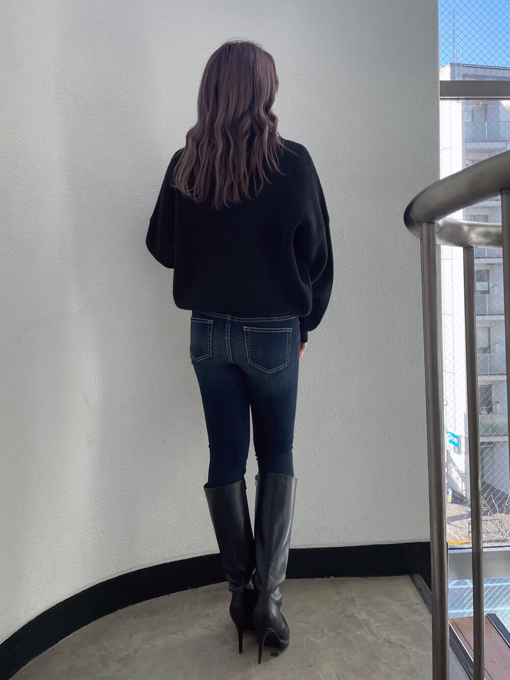 ブラック系のブーツ、ブルー系のデニムパンツ、ブラック系のニット/セーターを着用したレディースの冬コーディネートの2枚目の写真