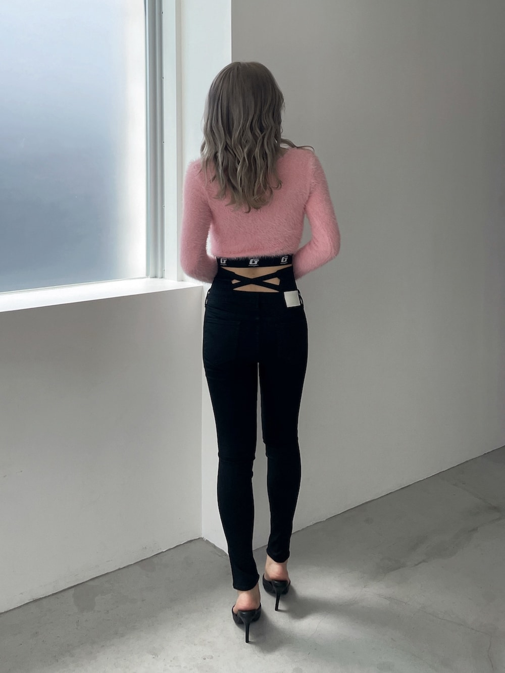 ピンク系のニット/セーター、ブラック系のデニムパンツ、ブラック系のパンプスを着用したレディースの冬コーディネートの3枚目の写真