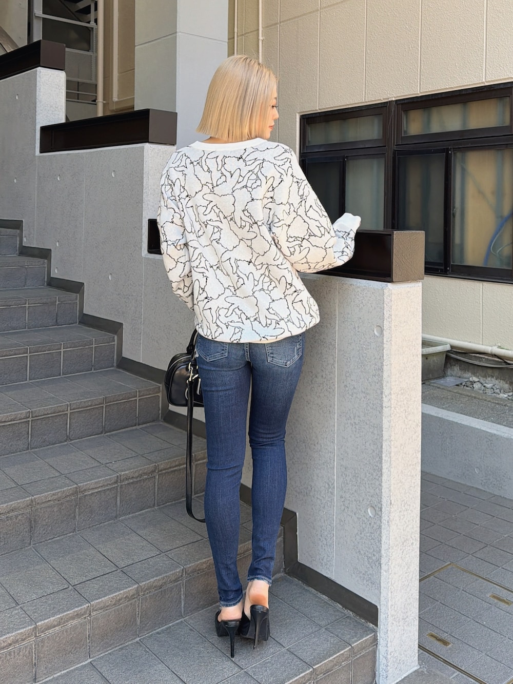 ホワイト系のニット/セーター、ブルー系のデニムパンツ、ブラック系のハンドバッグを着用したレディースの冬コーディネートの2枚目の写真