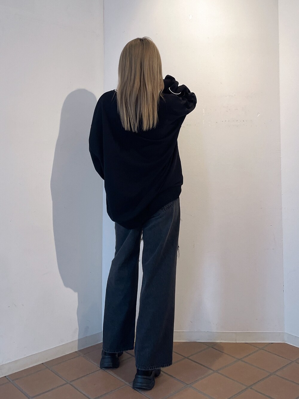 ブラック系のスウェット、ブラック系のデニムパンツ、ブラック系のブーツを着用したレディースの秋コーディネートの3枚目の写真