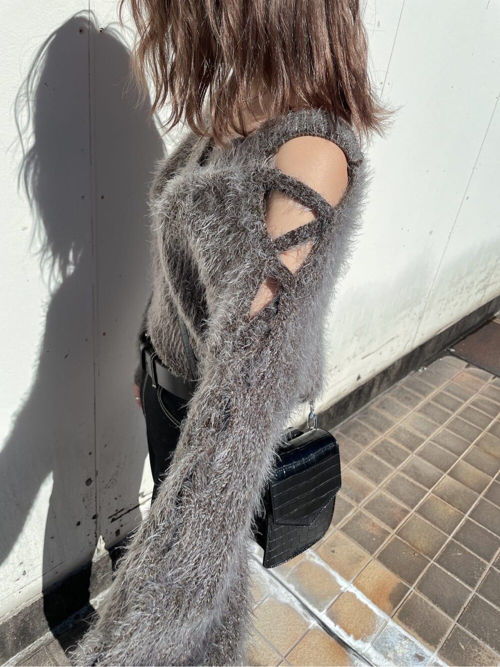 グレー系のニット/セーター、ブラック系のブーツ、ブラック系のデニムパンツを着用したレディースの秋コーディネートの5枚目の写真