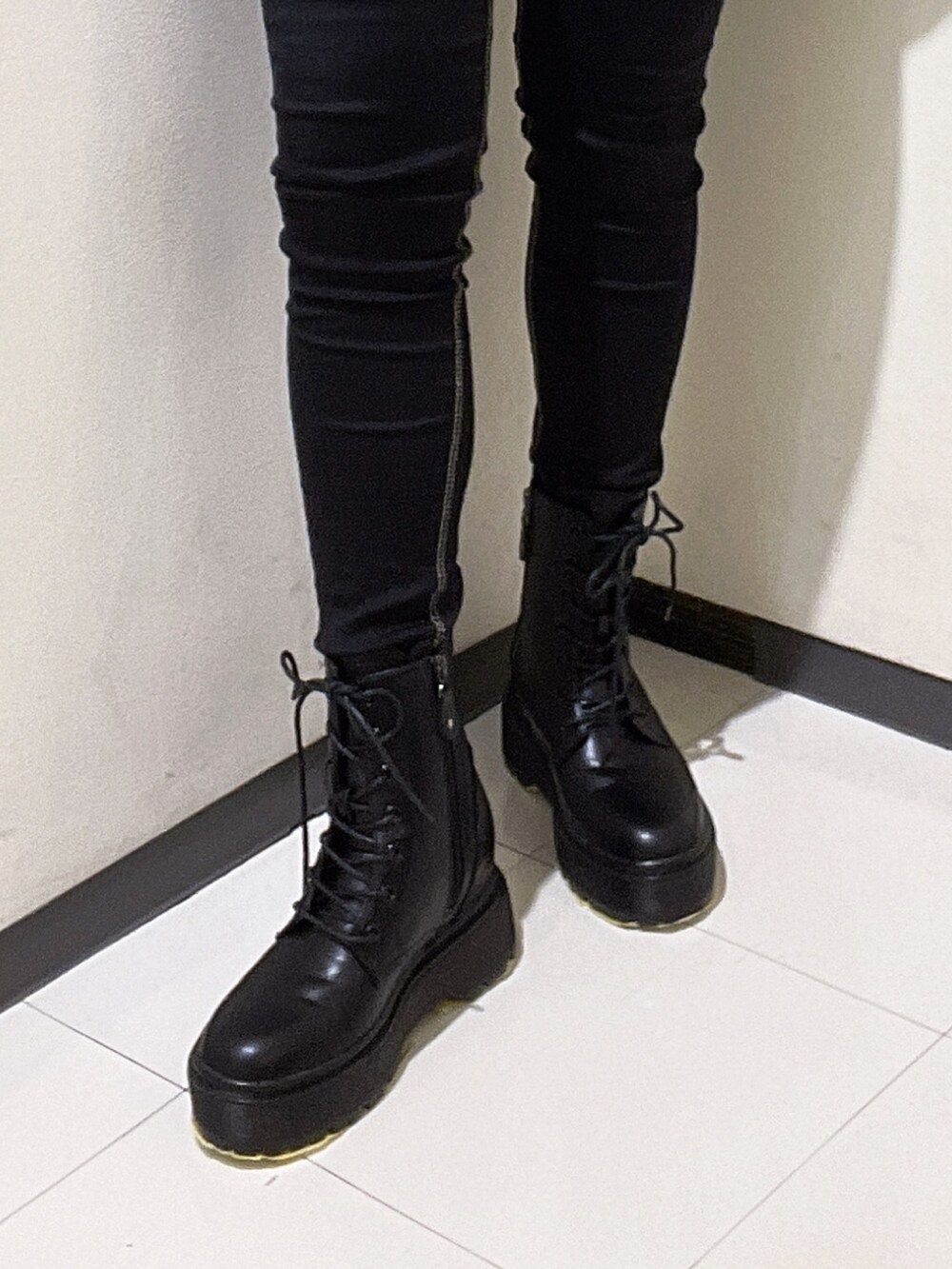 ホワイト系のスウェット、ブラック系のデニムパンツ、ブラック系のブーツを着用したレディースの秋コーディネートの7枚目の写真