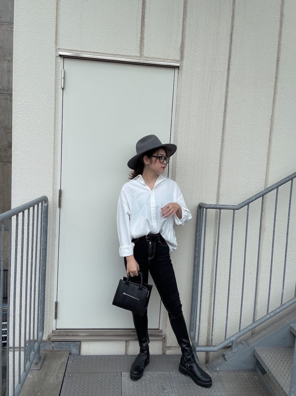 ブラック系のハンドバッグ、ブラック系のデニムパンツ、ホワイト系のシャツ/ブラウスを着用したレディースの秋コーディネートの2枚目の写真