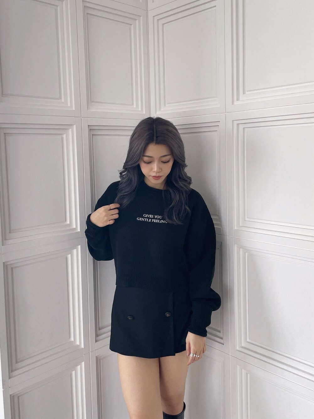 ブラック系のニット/セーター、ブラック系のスカート、ブラック系のブーツを着用したレディースの秋コーディネートの4枚目の写真