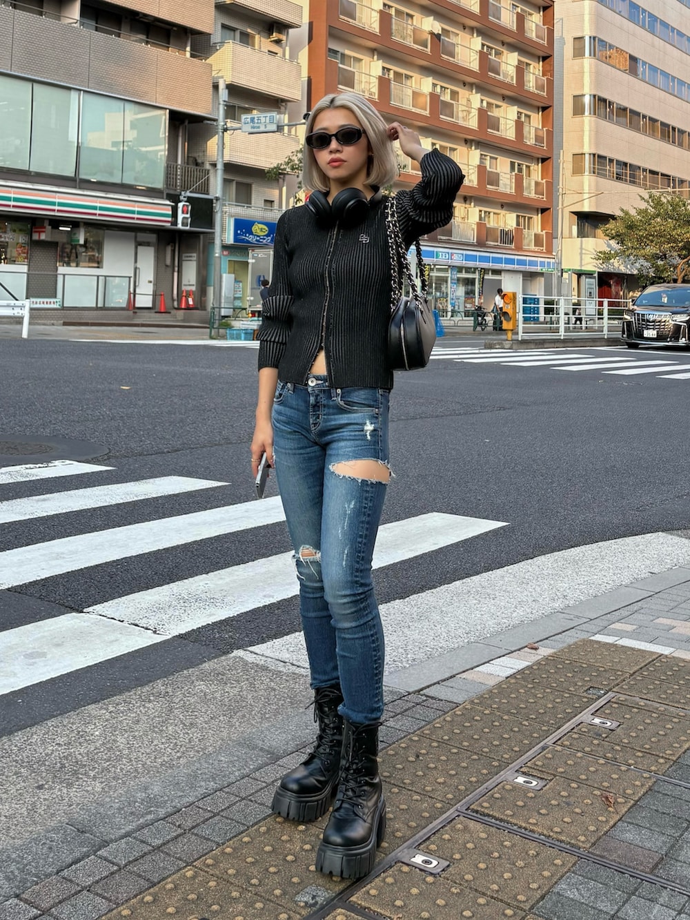 ブラック系のニット/セーター、ブルー系のデニムパンツ、ブラック系のブーツを着用したレディースの秋コーディネートの3枚目の写真