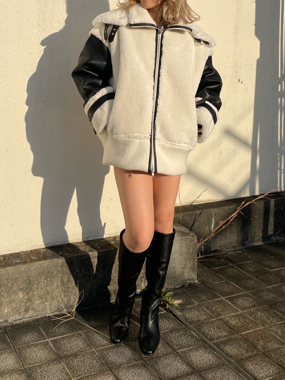 ホワイト系のブルゾン、ブラック系のブーツを着用したレディースの秋コーディネートの3枚目の写真
