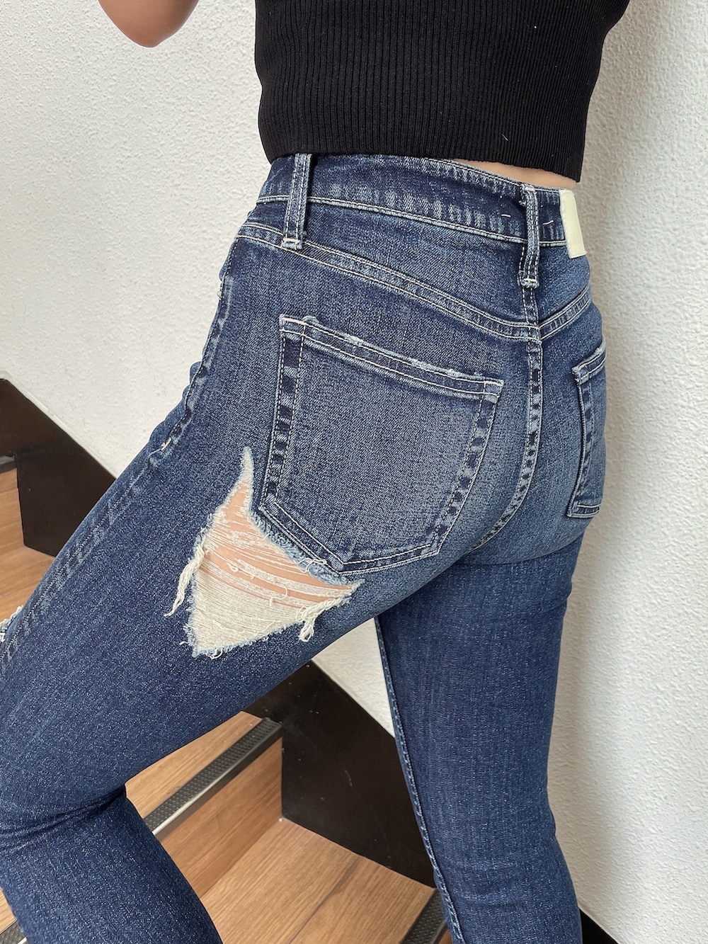 ブラック系のニット/セーター、ホワイト系のハンドバッグ、ブルー系のデニムパンツを着用したレディースの春コーディネートの7枚目の写真