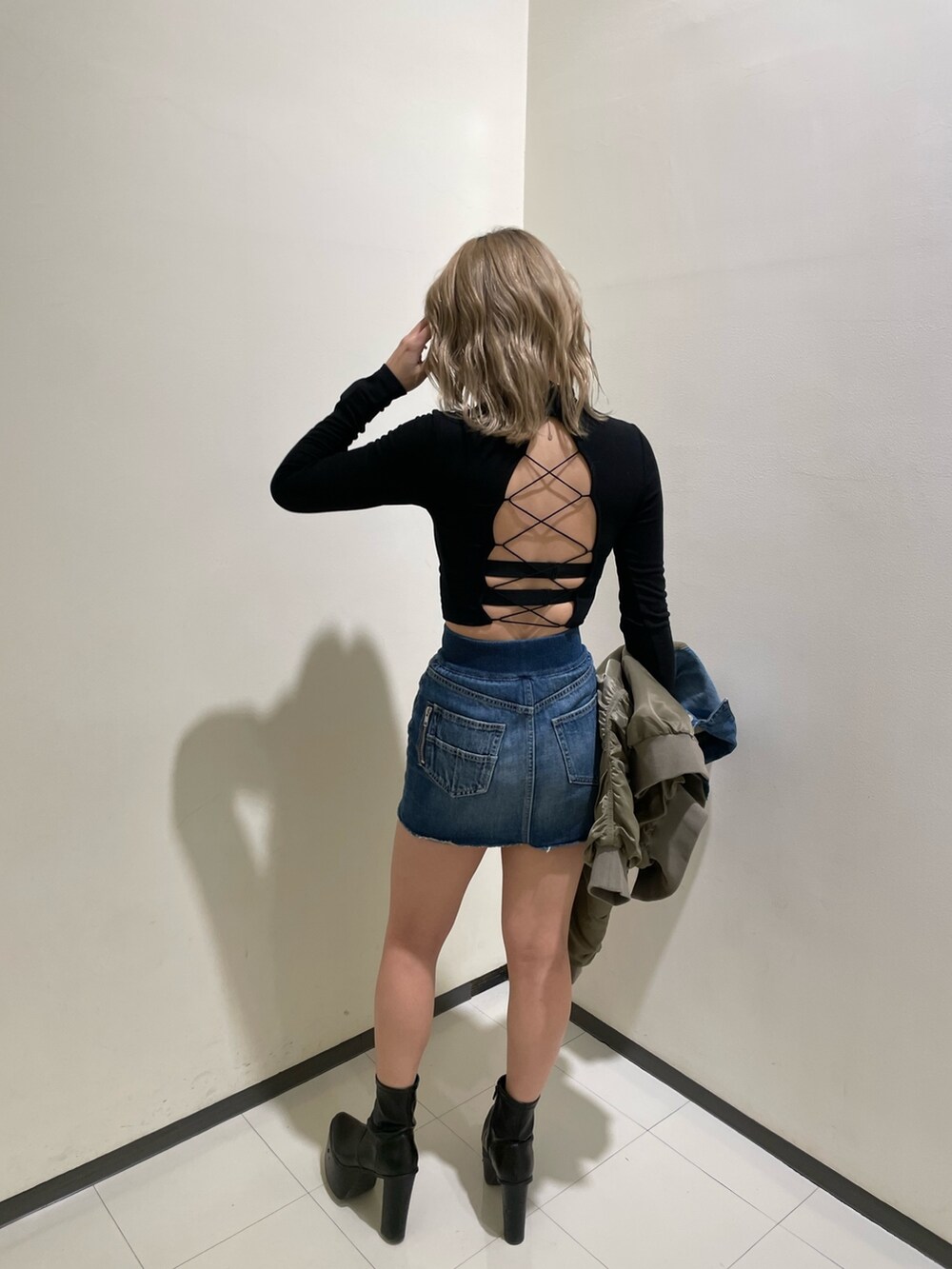 ブルー系のデニムスカート、ブラック系のブーツ、ブラック系のTシャツ/カットソーを着用したレディースの冬コーディネートの6枚目の写真