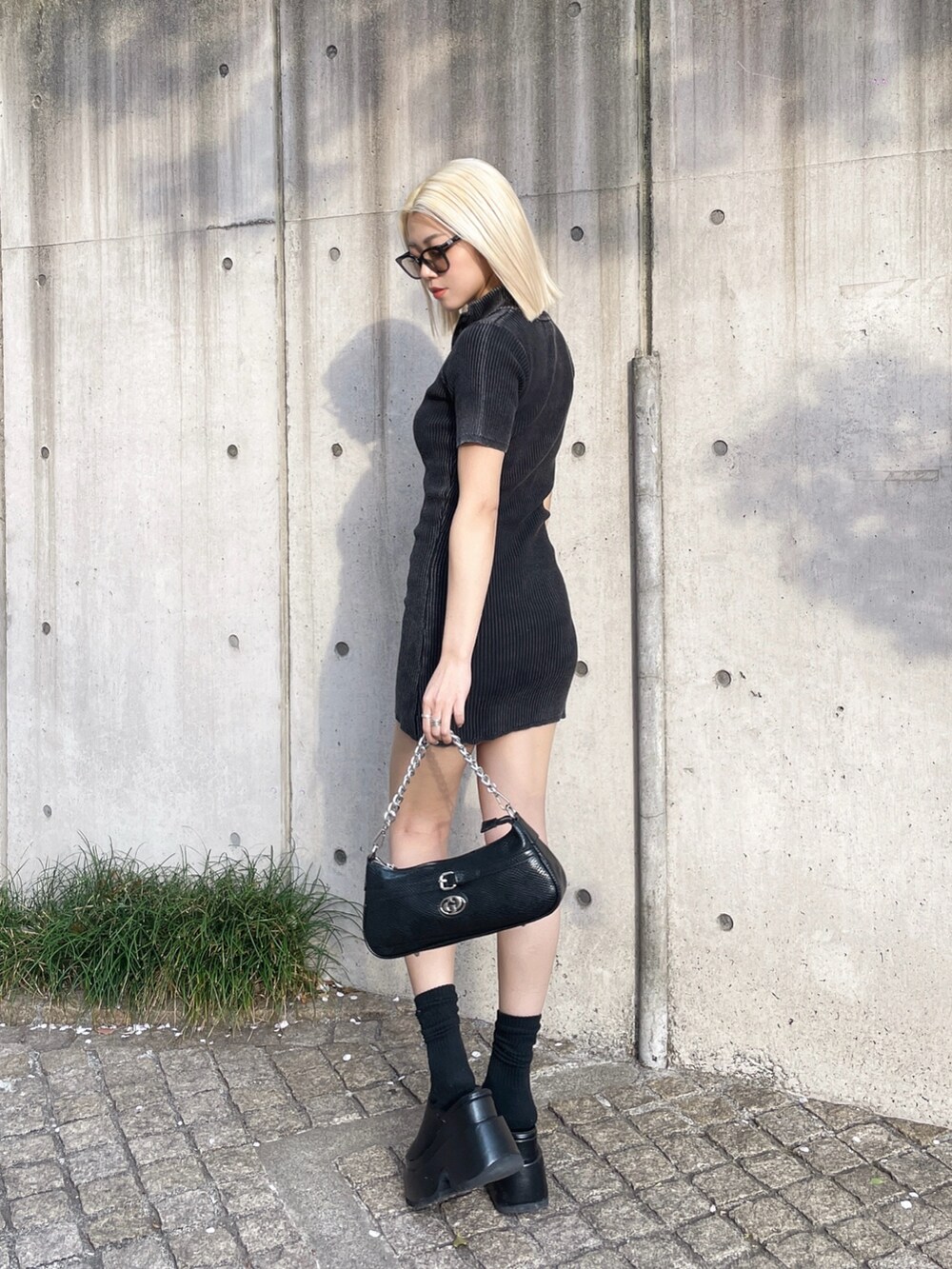 ブラック系のワンピース、ブラック系のサンダル、ブラック系のハンドバッグを着用したレディースの春コーディネートの2枚目の写真