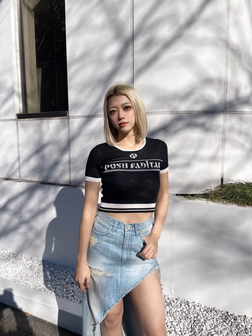 ブラック系のニット/セーター、ブルー系のデニムスカート、ブラック系のパンプスを着用したレディースの春コーディネートの2枚目の写真