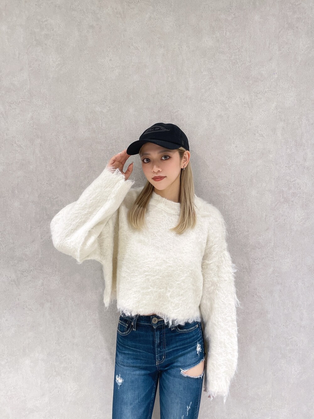 ホワイト系のニット/セーター、ブルー系のデニムパンツ、ブラック系のブーツを着用したレディースの冬コーディネートの4枚目の写真