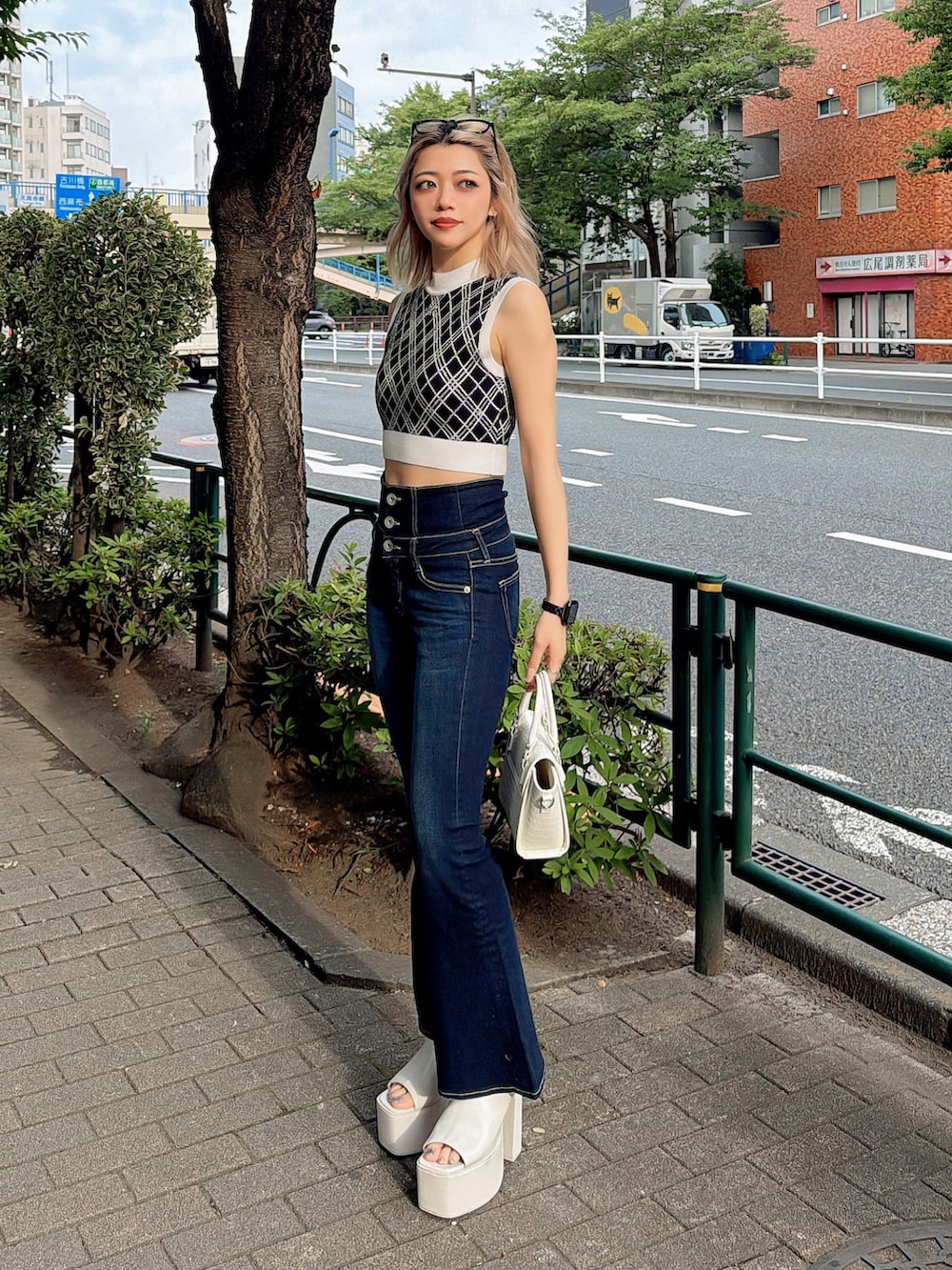 ブラック系のニット/セーター、ブルー系のデニムパンツ、ホワイト系のハンドバッグを着用したレディースの夏コーディネートの2枚目の写真