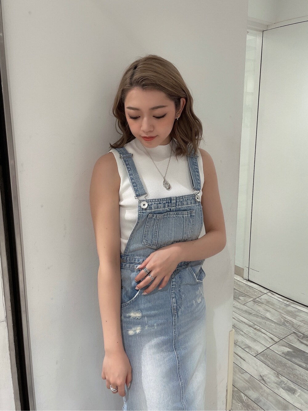 ブルー系のジャンパースカート、ベージュ系のサンダル、ホワイト系のニット/セーターを着用したレディースの春コーディネートの4枚目の写真