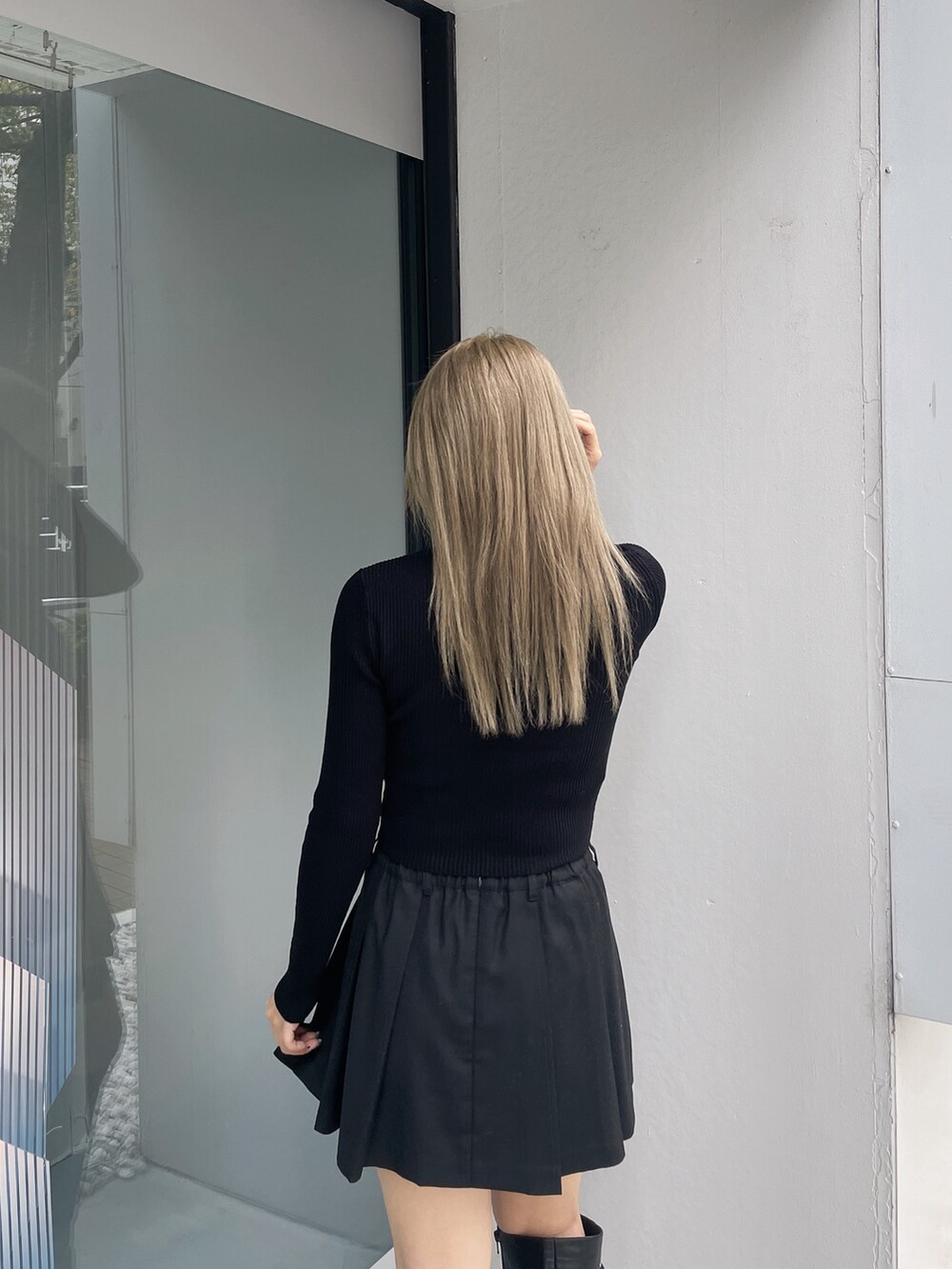 ブラック系のニット/セーター、ブラック系のスカート、ブラック系のブーツを着用したレディースの秋コーディネートの5枚目の写真